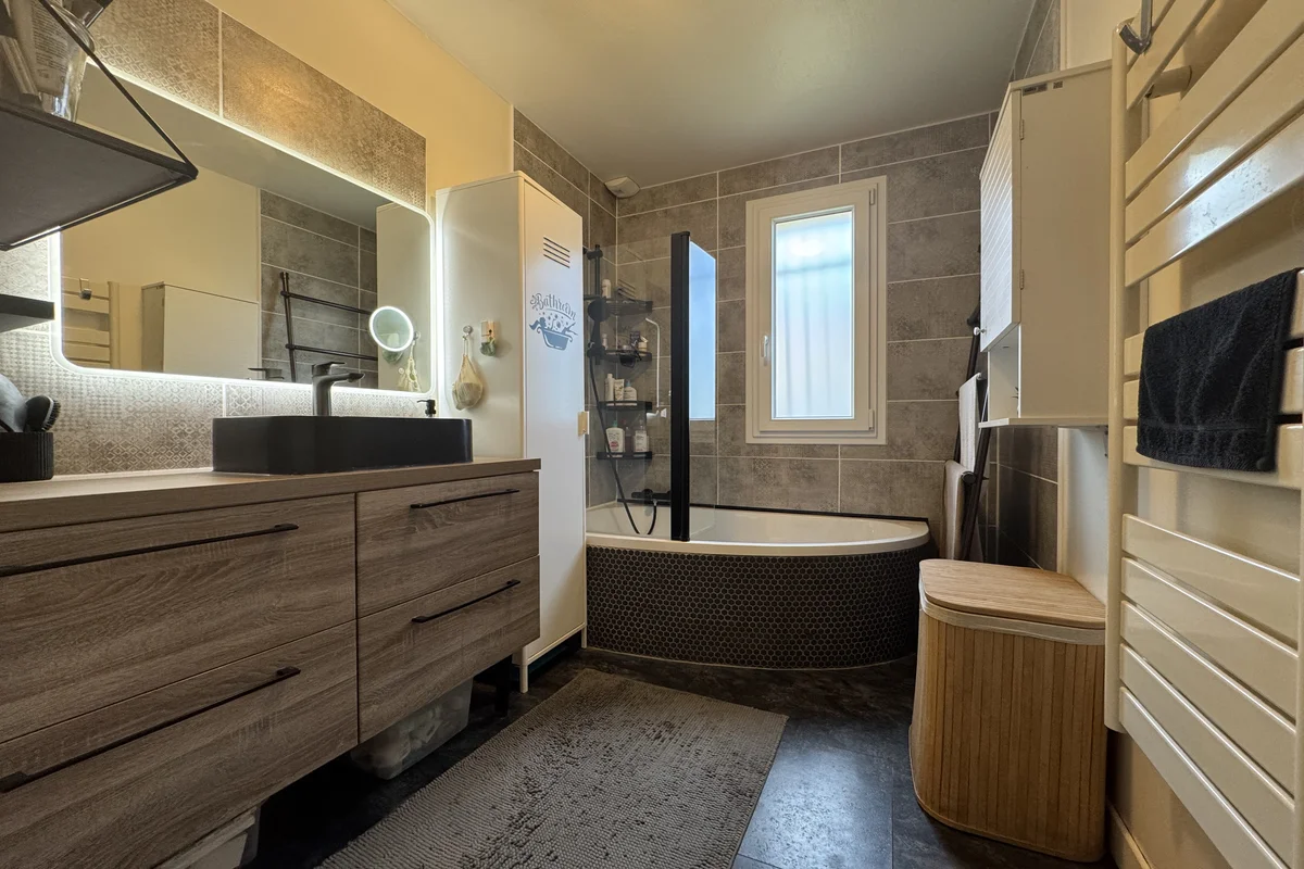 Salle de bains avec baignoire d angle et meuble vasque dans une maison à Annecy-le-Vieux