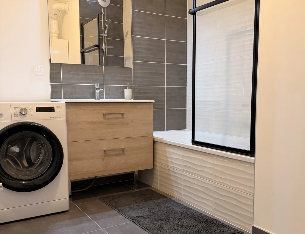 Salle de bains moderne avec baignoire dans un appartement récent à Cuvat