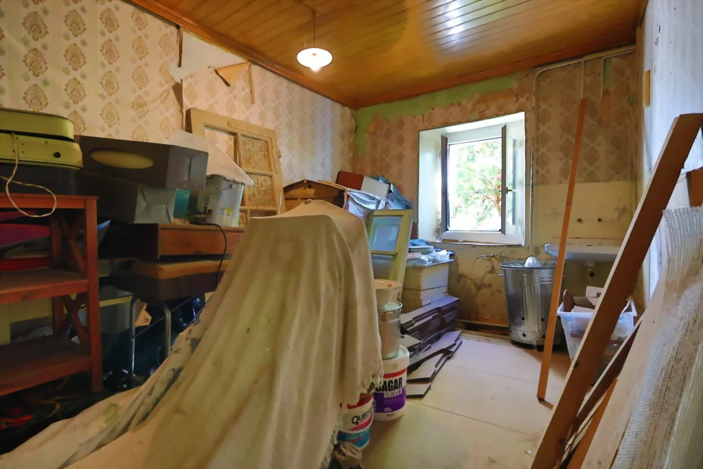 Pièce avec fenêtre, plafond en lambris bois et papier peint ancien, à rénover